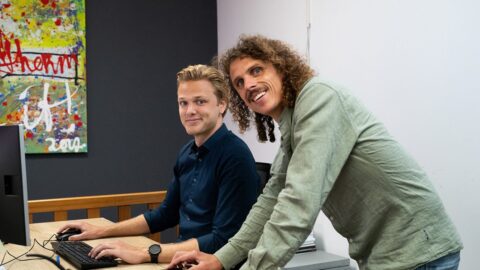 Twee medewerkers van Engeltherm kijken lachend vanaf het bureau naar de camera